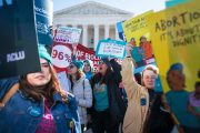 Demonstrators shout slogans and hold banners in front of the Supreme Court.