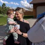 Mollie Wetzel nuzzles her 9 month old Olivia as they receive a can of baby from Alexis Adams.