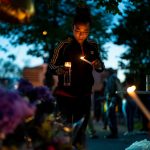 Alexis Rodriguez lights candles in front of a memorial for the Buffalo mass shooting.