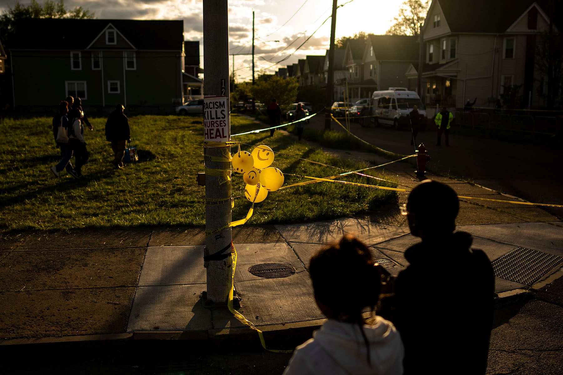 Balloons are seen attached to an electric pole. On the pole a sign reads "Racism Kills Nurses Heal"