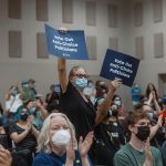 Supporters of candidate Jessica Cisneros clap and hold up signs that read 