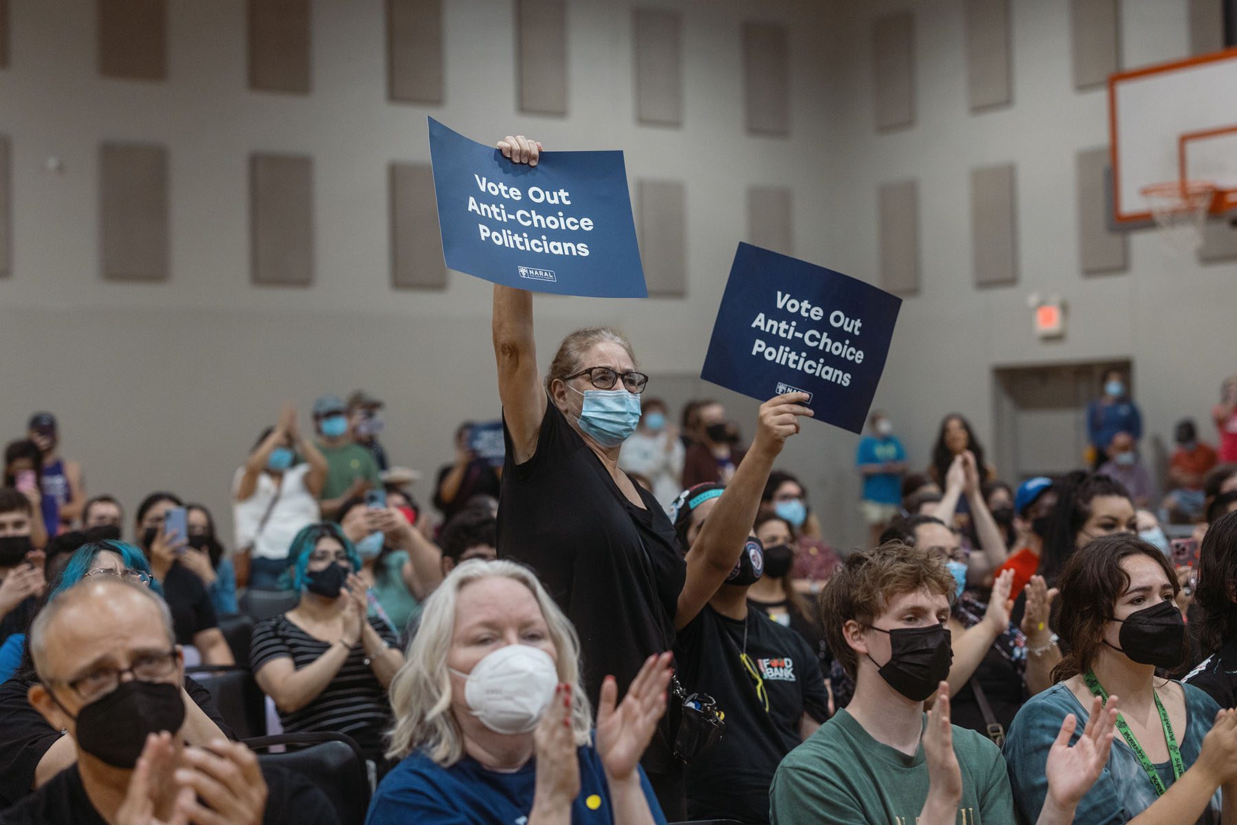 Supporters of candidate Jessica Cisneros clap and hold up signs that read "Vote Out Anti-Choice Politicians"