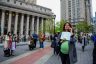 A visibly pregnant person holds a sign that reads 