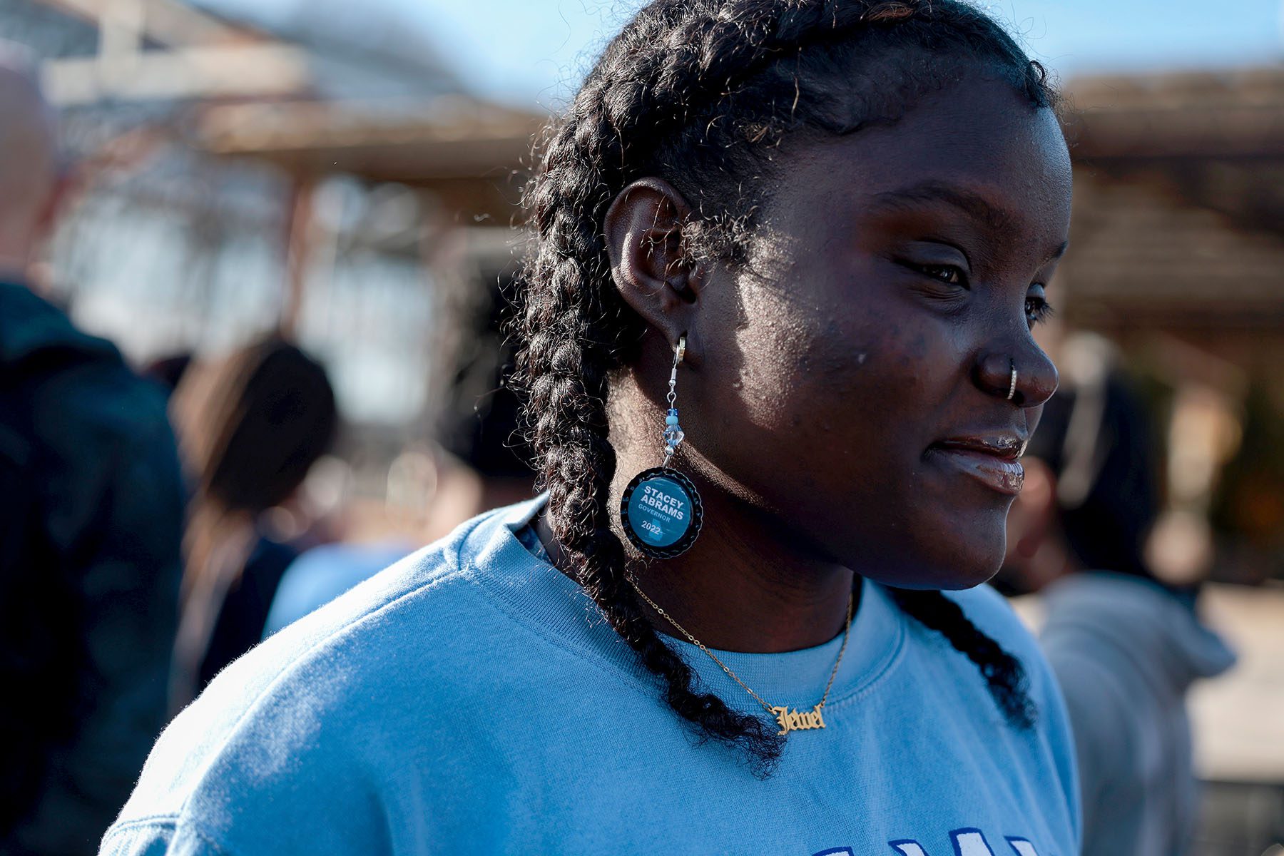 Jewel M. Lucien wears Stacey Abrams earrings. They're round and read "Stacey Abrams Governor 2022."