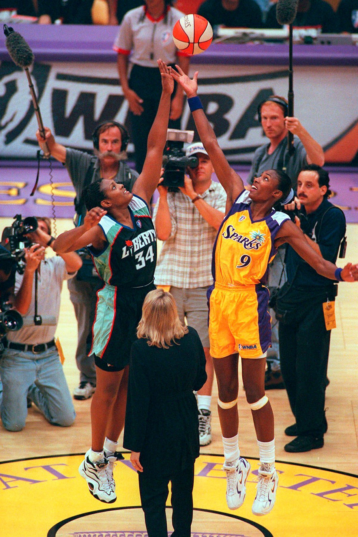 Los Angeles Sparks' Lisa Leslie (right) and New York Liberty's Kym Hampton leap for the ball during the opening tipoff during the first half of the inaugural WNBA basketball game.