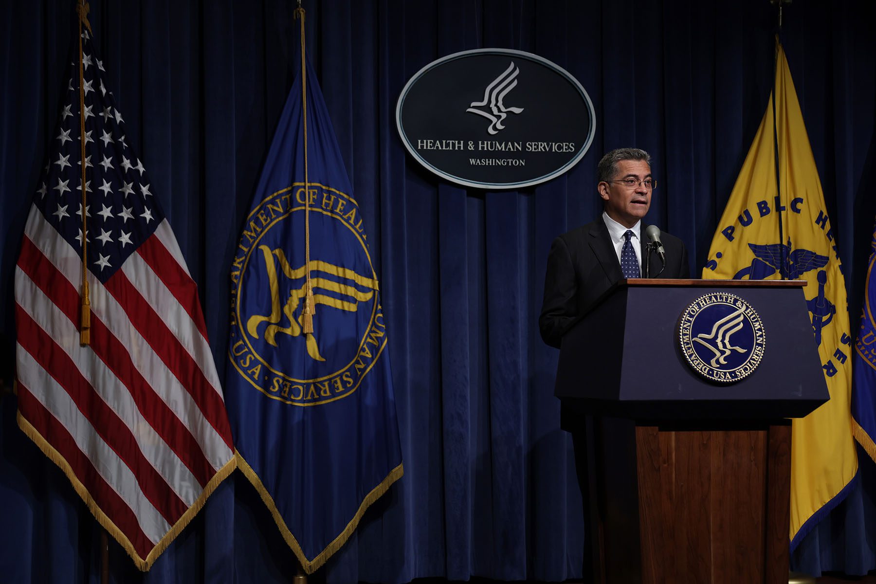 Xavier Becerra speaks from a podium during a news conference.