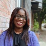 Smiling portrait of Atiyah Harmon leaning against a brick wall