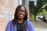 Smiling portrait of Atiyah Harmon leaning against a brick wall