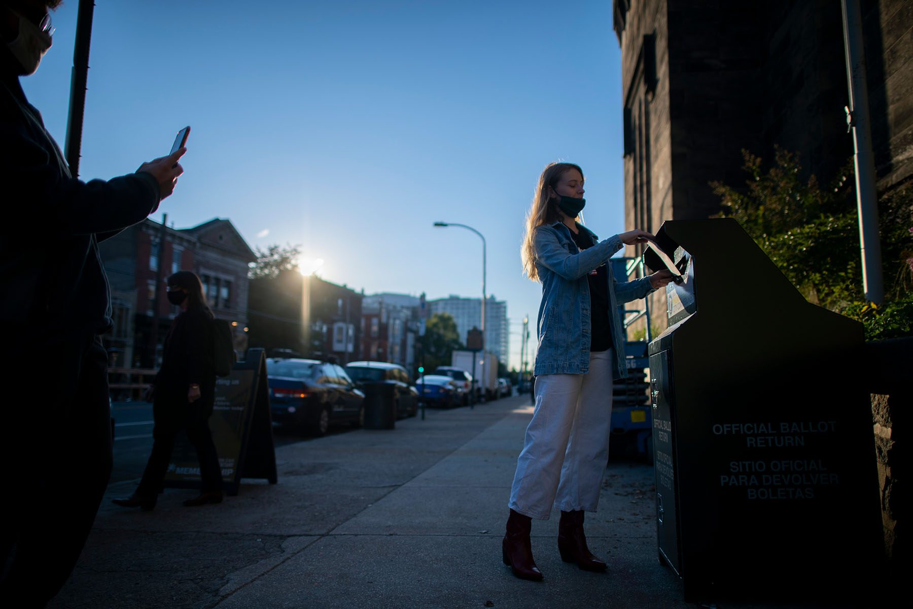 A woman casts her early voting ballot at drop box.