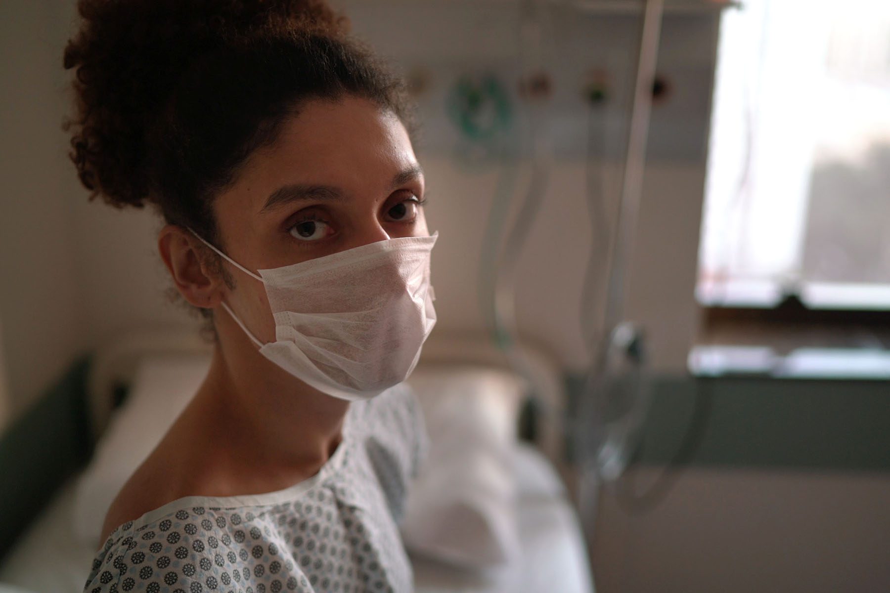 Portrait of genderqueer patient in a doctor's exam room wearing a face mask.