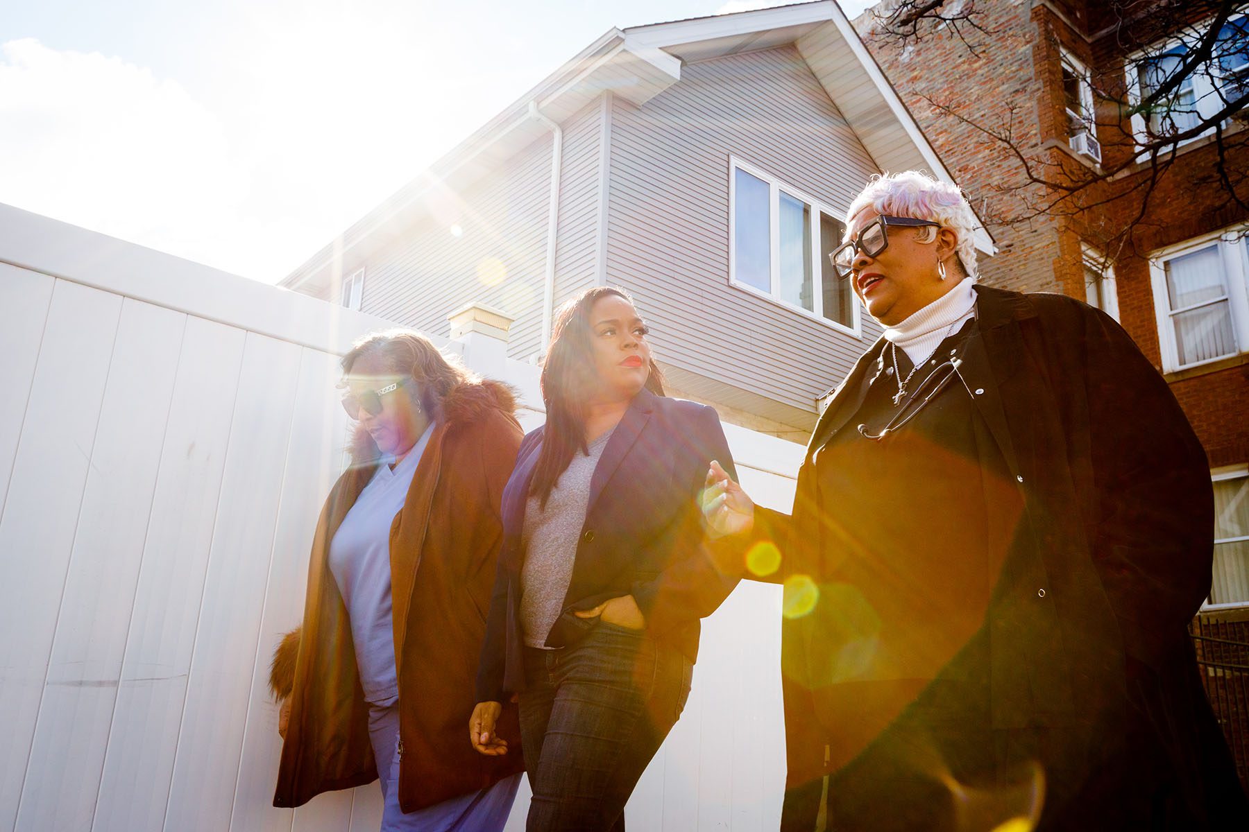 Kina Collins walks and speaks with two community members.