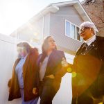 Kina Collins walks and speaks with two community members.