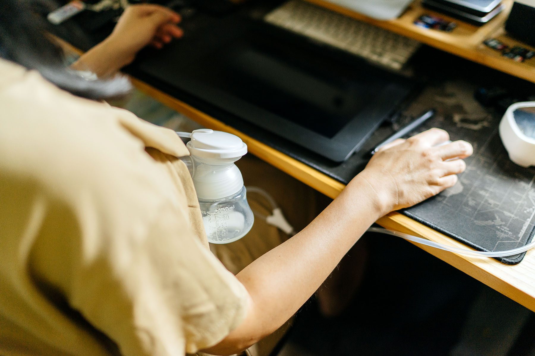 Person pumping breast milk while working on a computer.