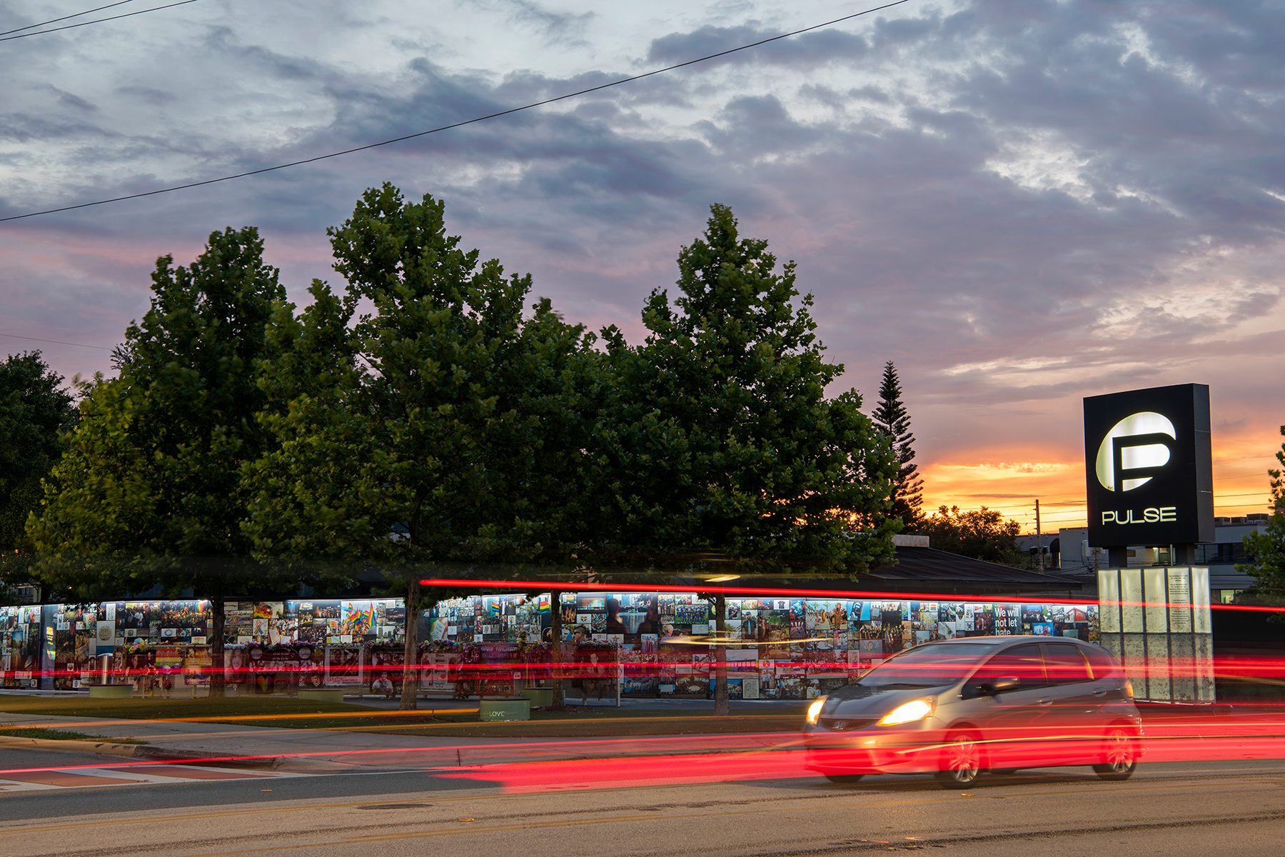 Cars drive by the Pulse Memorial at sunset