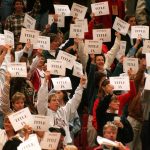 Members and supporters of the Women's Basketball Coaches Association demonstrate in support of Title IX by holding up printed signs that read 