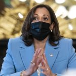 Vice President Kamala Harris wears a blue suit and black mask as she speaks at an event.