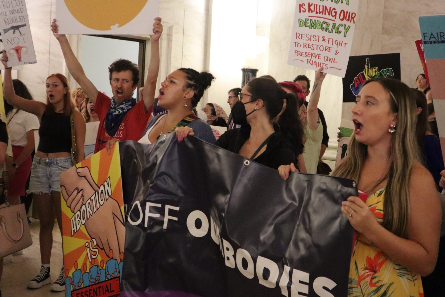 A group of people holding various signs protesting abortion restrictions.