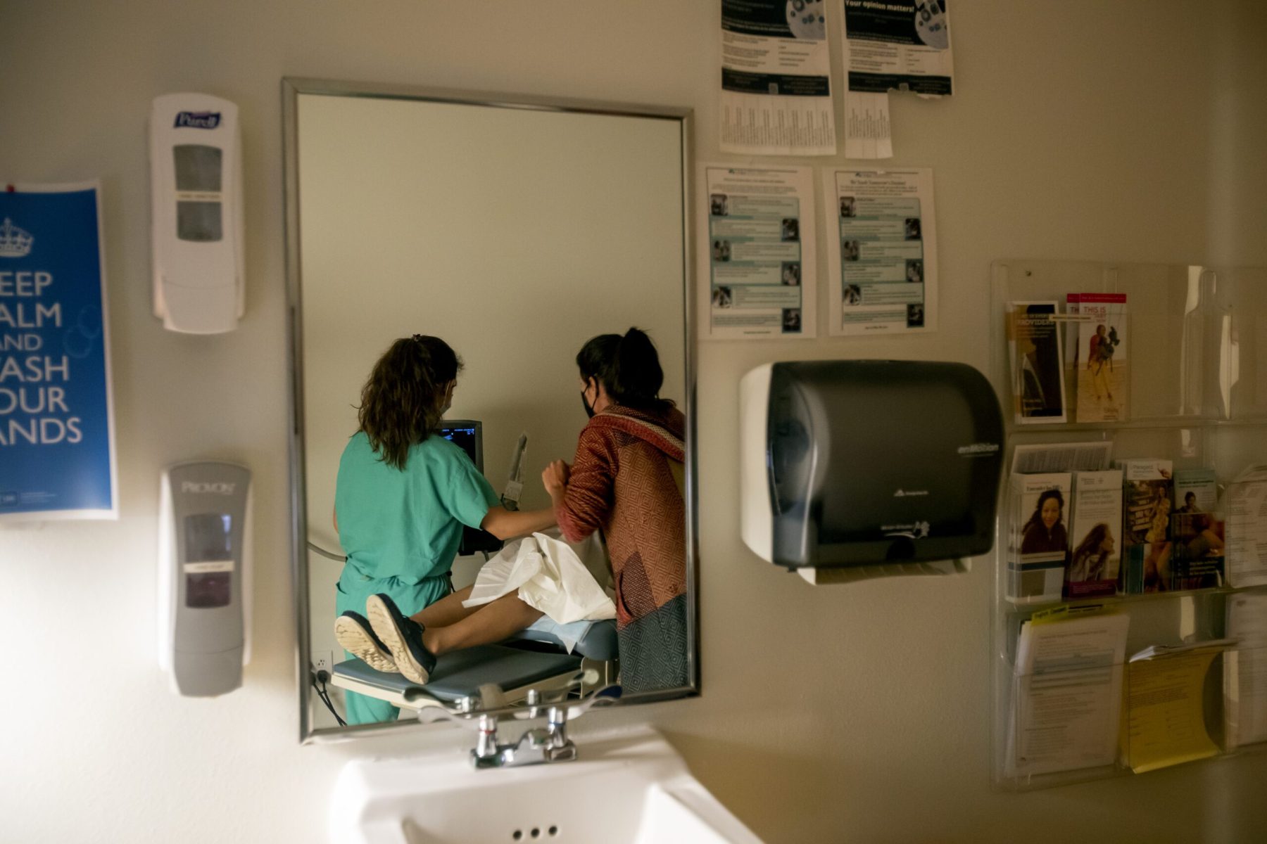 A family physician and her resident perform an ultrasound on a 39-year-old woman in a doctor's office.