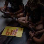 protesters sit around a yellow sign for abortion rights inside the indiana state capitol in indianapolis