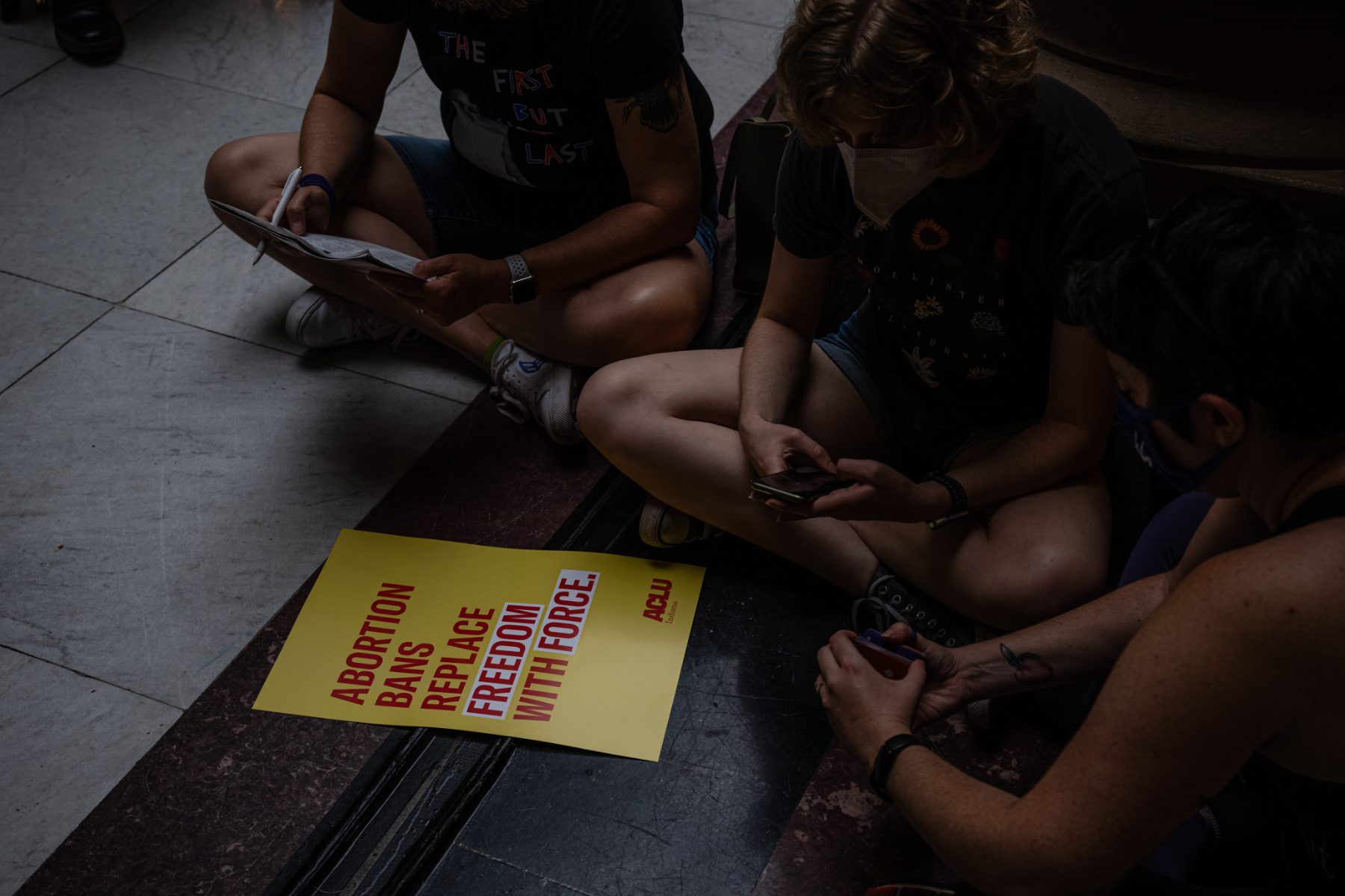 protesters sit around a yellow sign for abortion rights inside the indiana state capitol in indianapolis