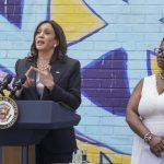 Kamala Harris talks in front of a colorful mural; assistant Pittsburgh city clerk Kimberly Clark-Baskin stands to her side