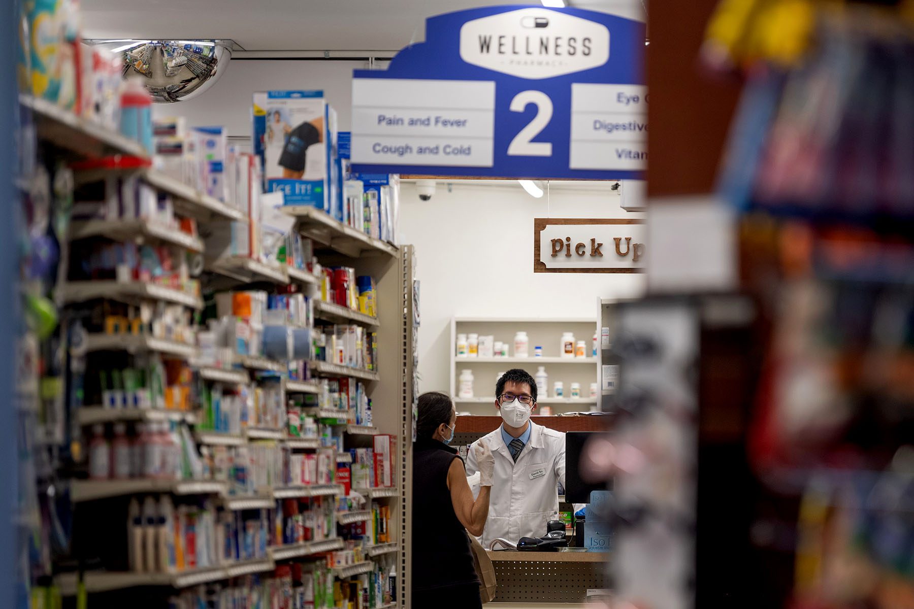 A woman speaks to a pharmacist inside a pharmacy.