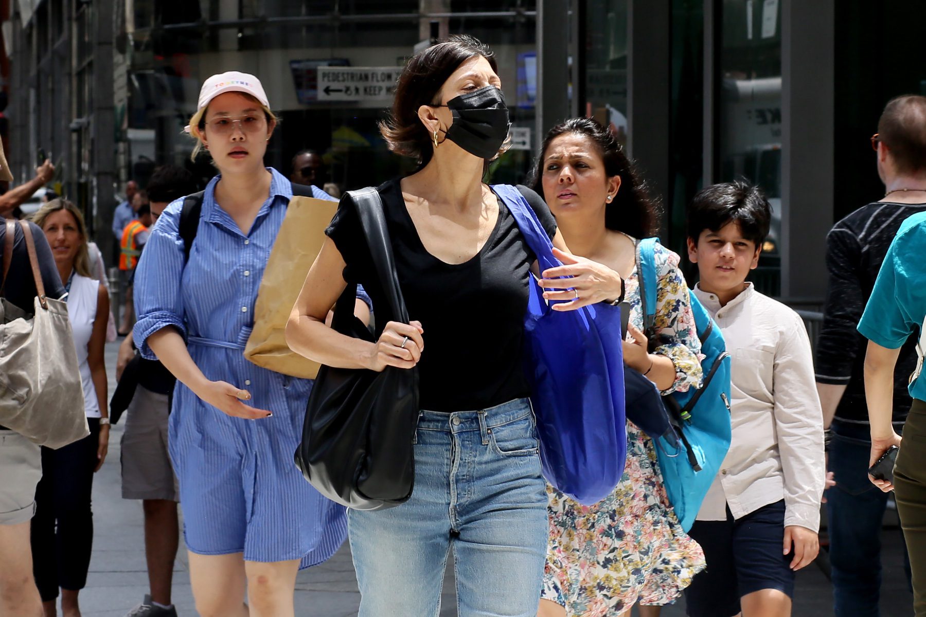 A group of three women walk on a crowded street.