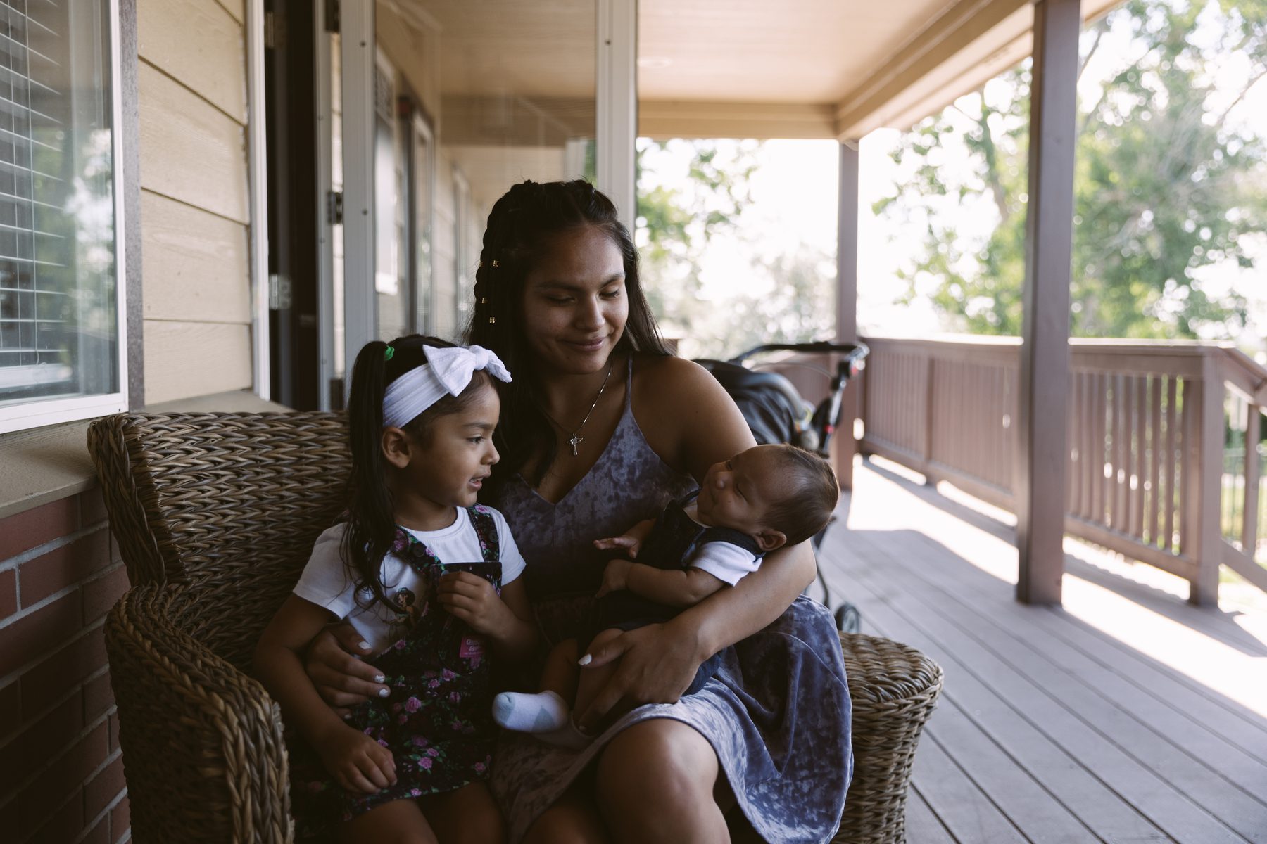 LaTavia BigBack sits on a porch with her two children.