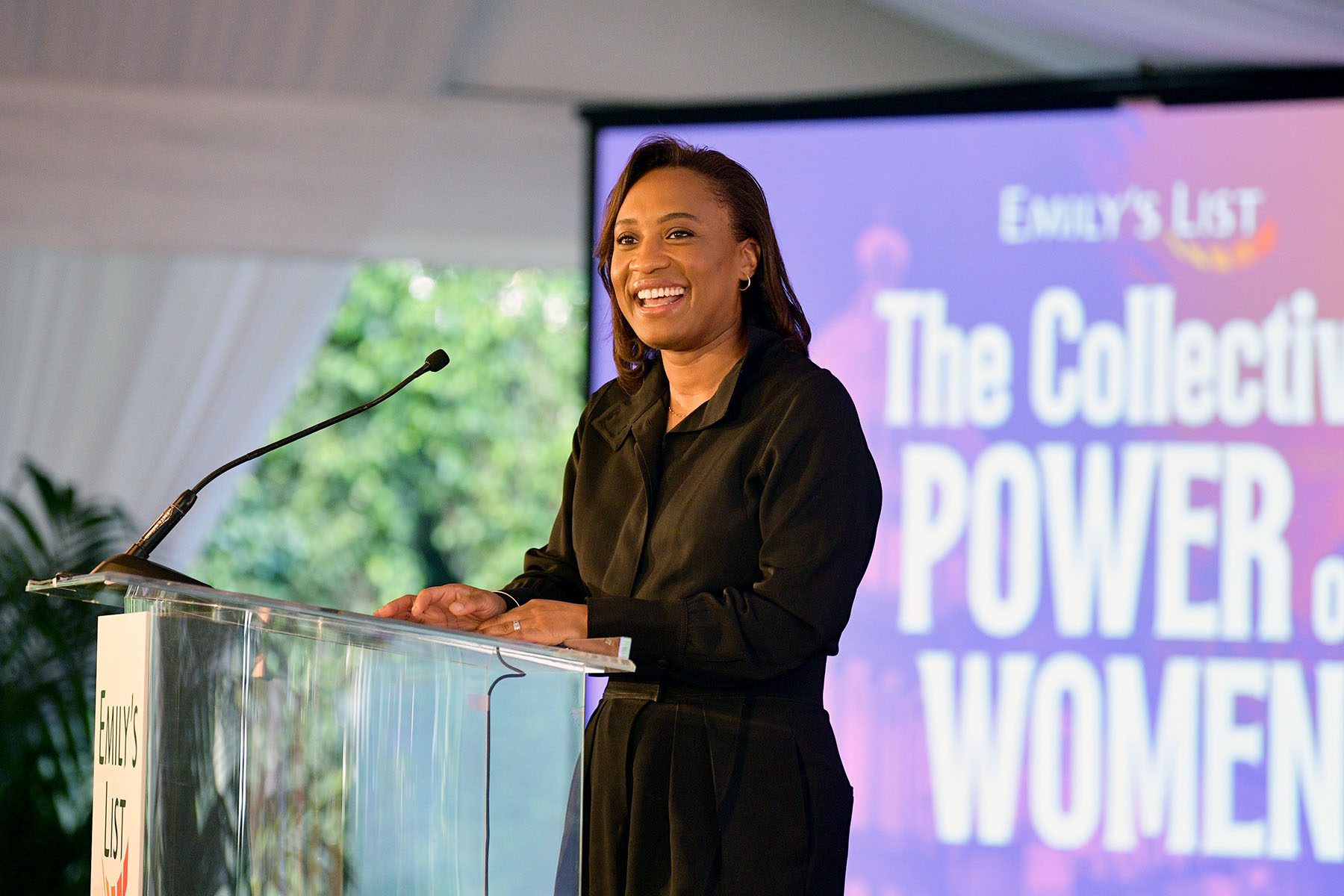 Laphonza Butler speaks onstage. Behind her, a screen reads "The Collective Power of Women."