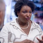 Stacey Abrams wearing a white top as she speaks to voters.