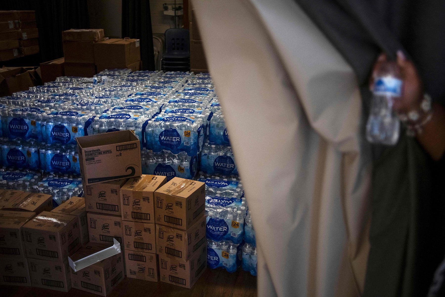 School Principal Cheryl Brown pulls back a curtain where they keep their bottled water for students.