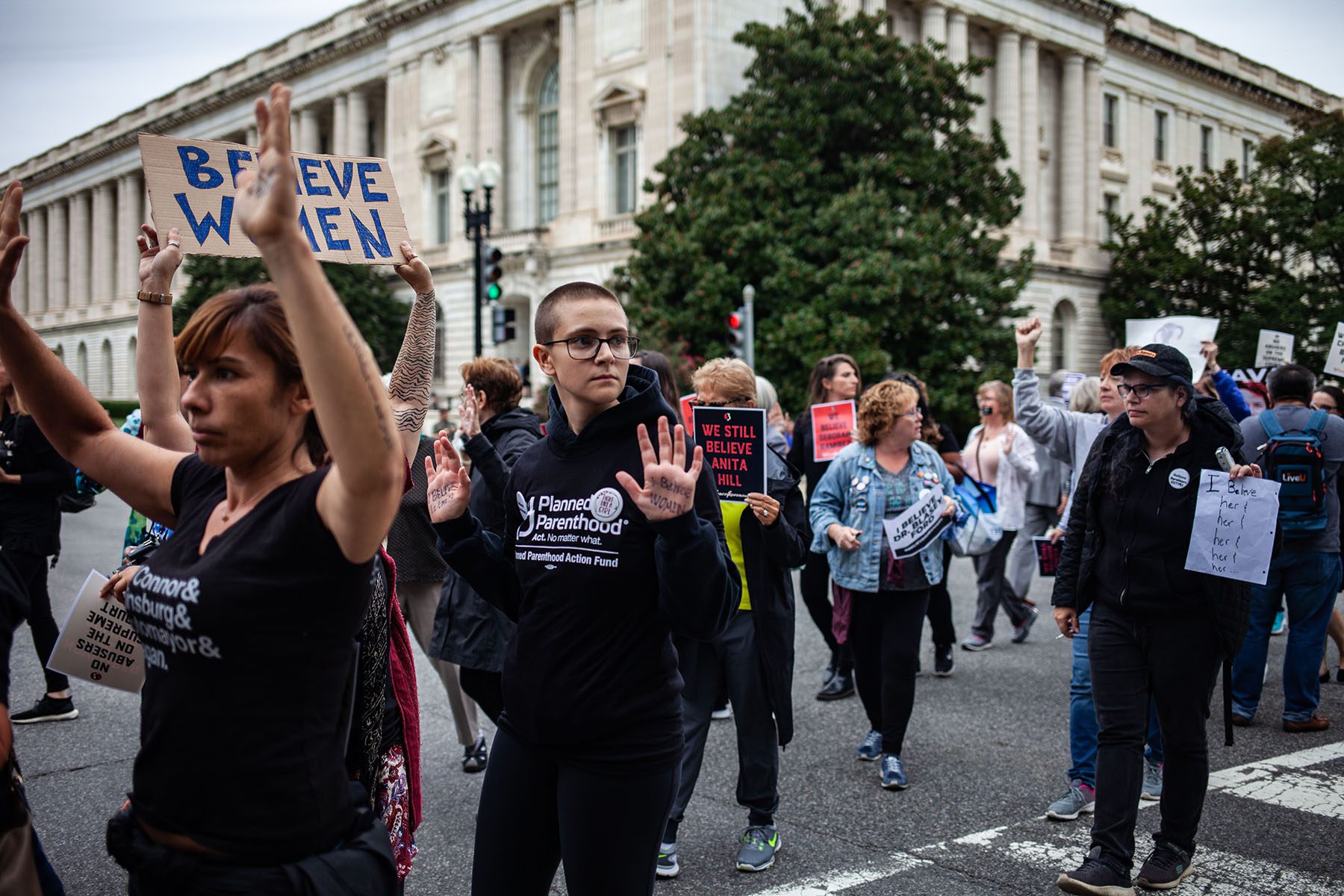 Protesters march towards the U.S. Capitol holding signs in support of Christine Blasey Ford.