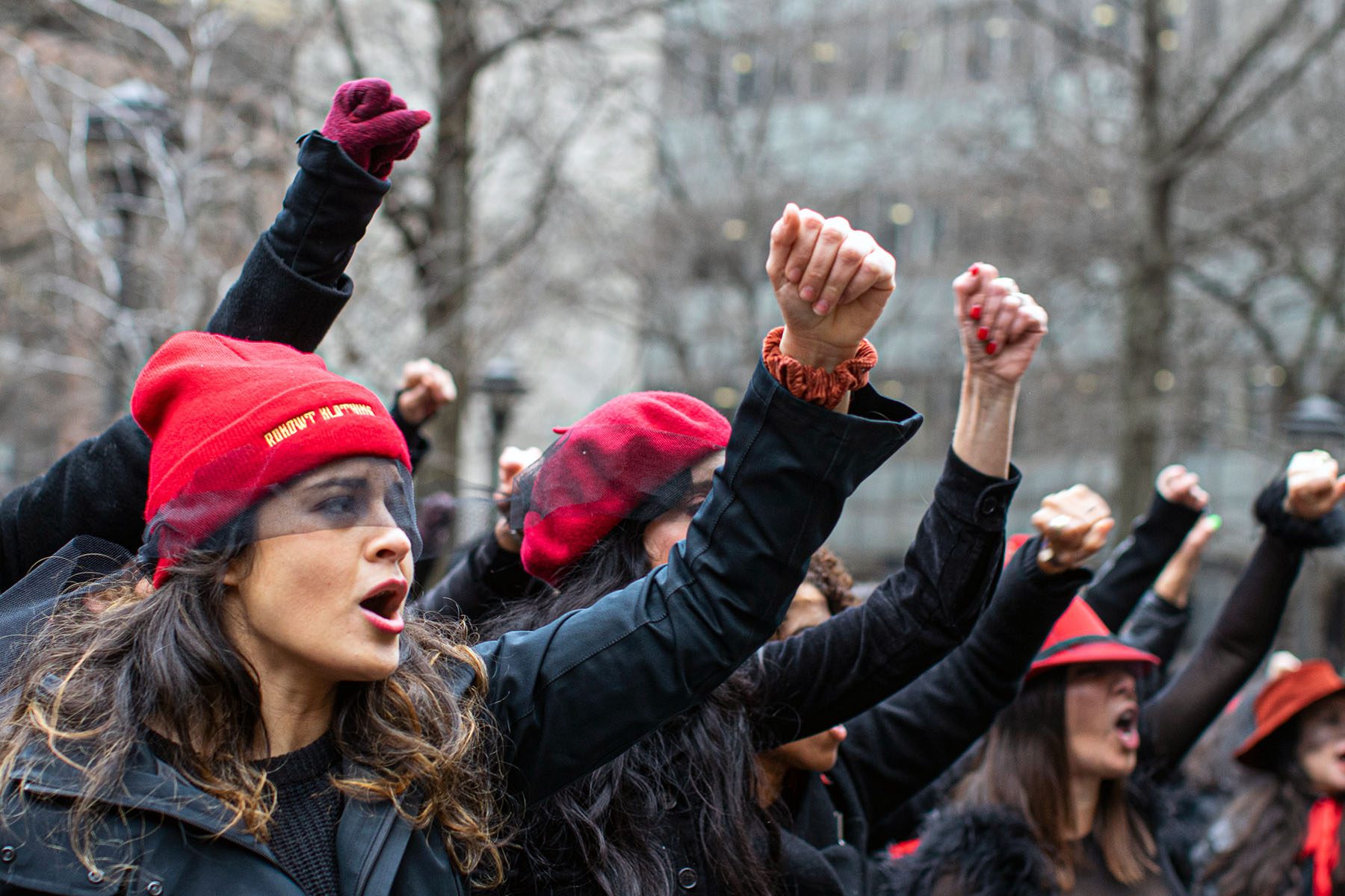 Women protest and sing songs with their fists in the air as Harvey Weinstein attends a pretrial session in New York City.