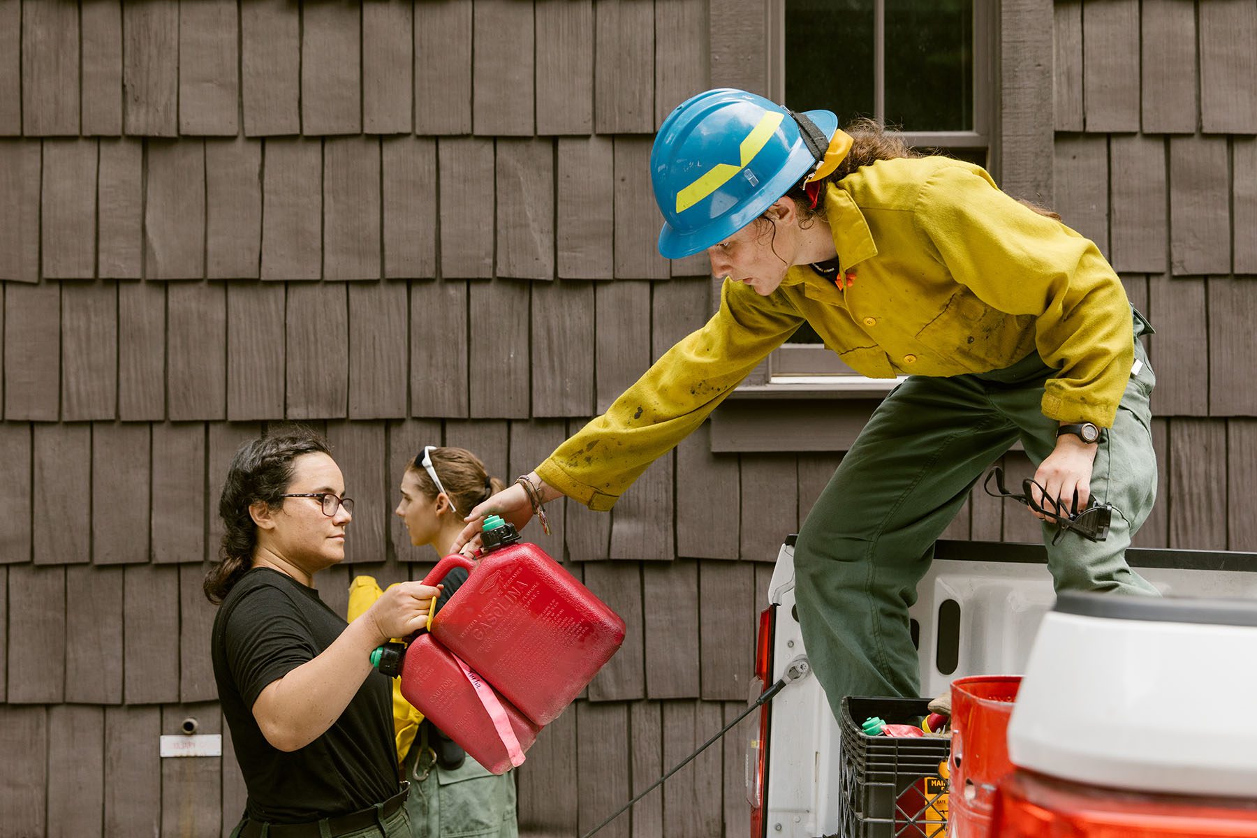 Cheyenne Haffner stands on top of a truck bed as Kathy Petersen passes her supplies.