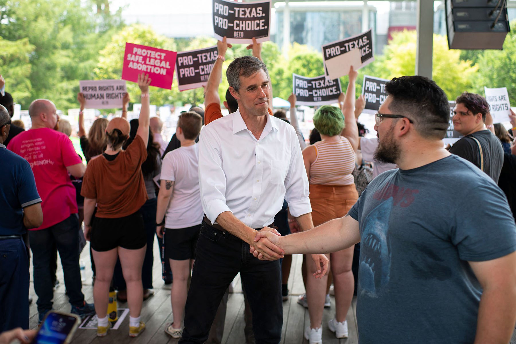 Beto O'Rourke shakes hands with an attendee prior to speaking at A Texas Rally for Abortion Rights. Attendees hold "pro-texas, pro-choice" behind him.