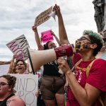 Abortion rights protesters chant and display signs at a demonstration.