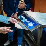 A person delivers their absentee ballot into a ballot drop.