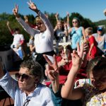 Attendees hold up two fingers during a rally encouraging voters to vote yes on Amendment 2.