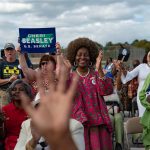 Cheri Beasley supporters smile, clap and cheer as she speaks at an event.