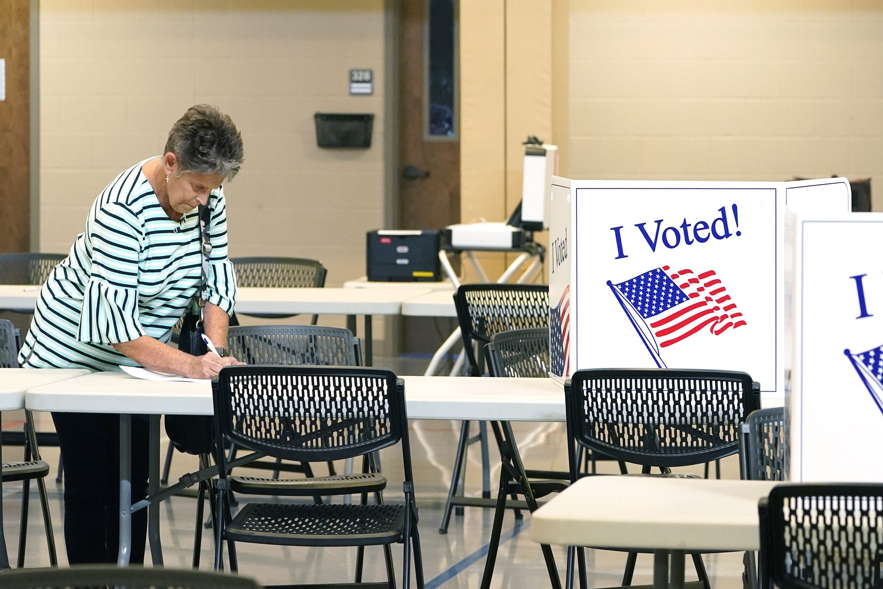 A woman fills out her ballot at a table.