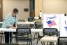 A woman fills out her ballot at a table.