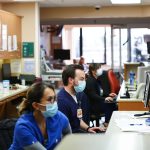 ICU nurses are seen working behind a reception desk.