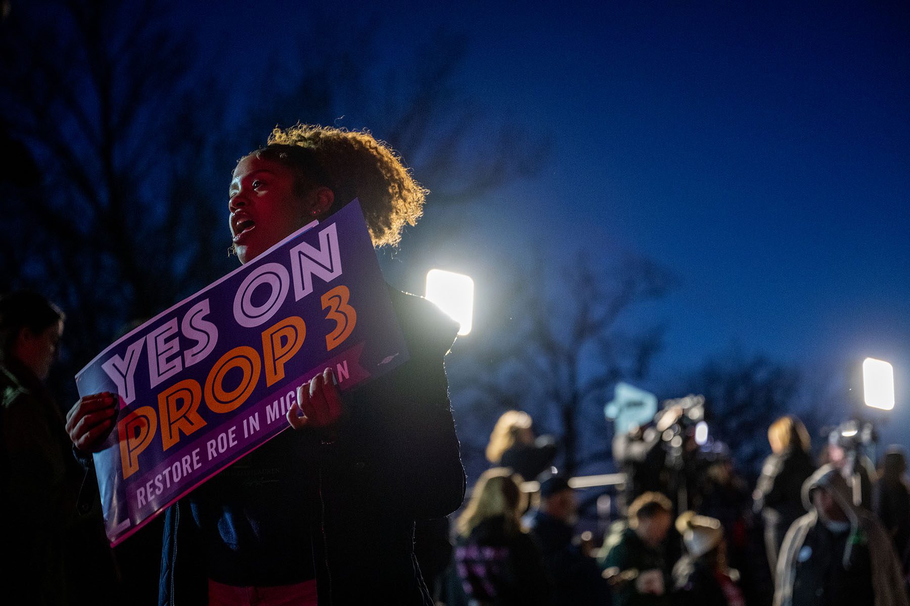 A supporter holding a "Yes on Prop 3, Restore Roe in Michigan" chants during a rally.