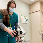 Lindee Miller turns on the camera attached to a colposcope.