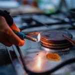 A person lights a gas burner inside a kitchen.