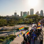 Demonstrators wave pride flags as they march across a bridge in protest of Florida's 