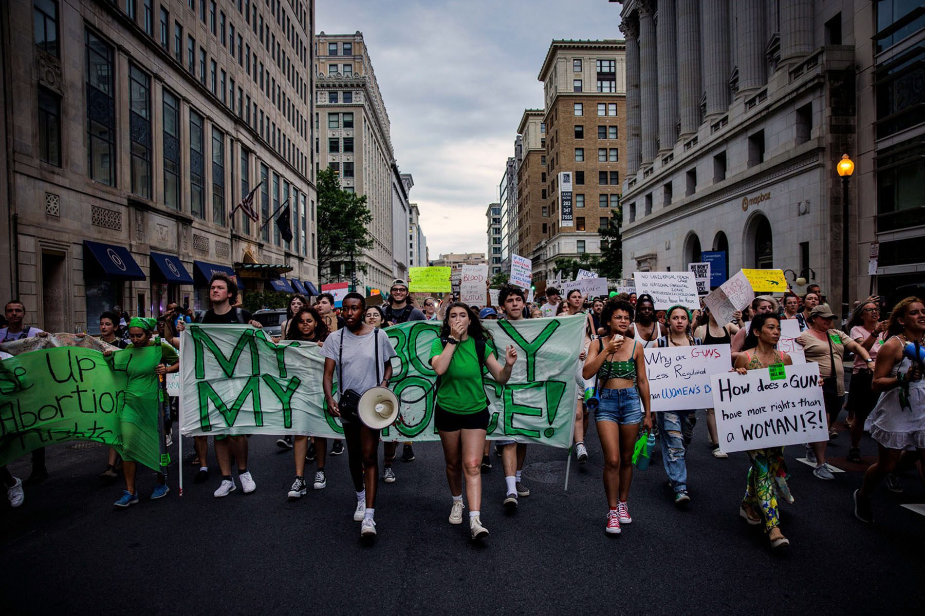 A large group of young abortion rights activists hold signs and banners as they march.