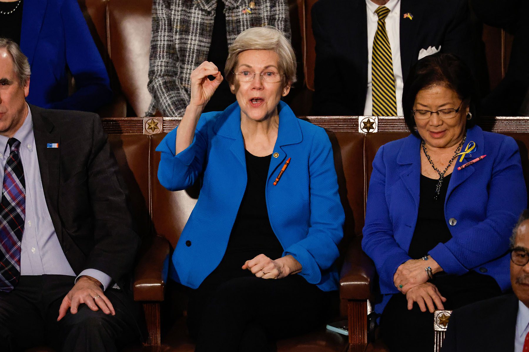 Sen. Elizabeth Warren wears a crayons pinned to her outfit to call attention the child care crisis as President Biden delivers his State of the Union address.