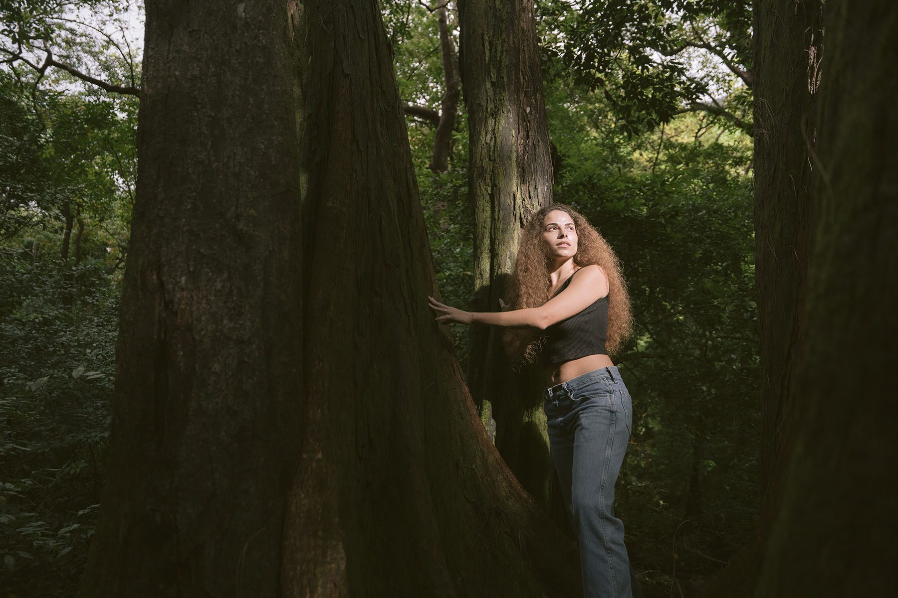 Sage Lenier poses for a portrait amongst trees.