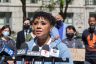 A woman speaks into press microphones at a rally.